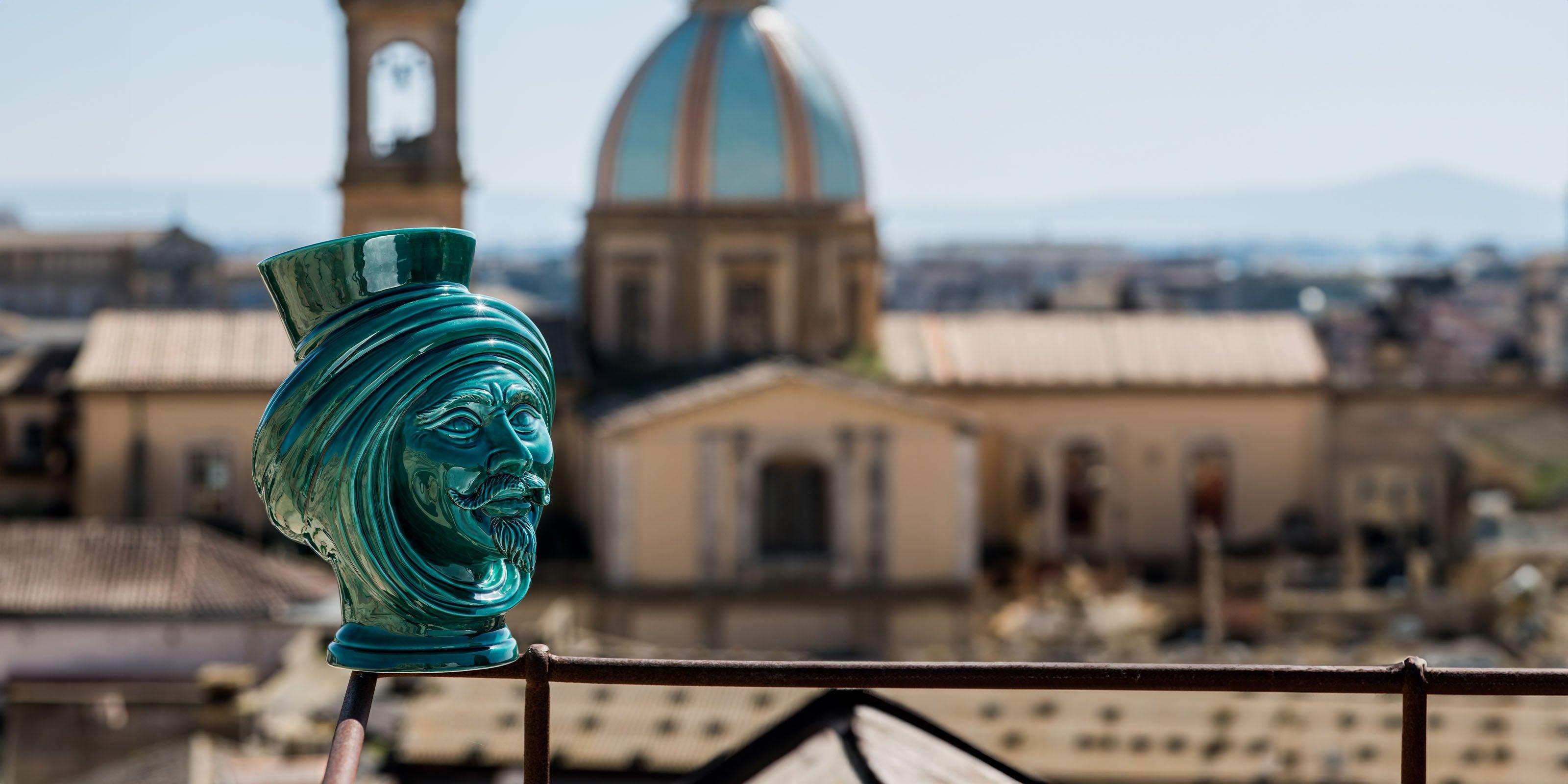 Testa di moro verde di ceramiche caltagirone fatti a mano su sfondo città storica