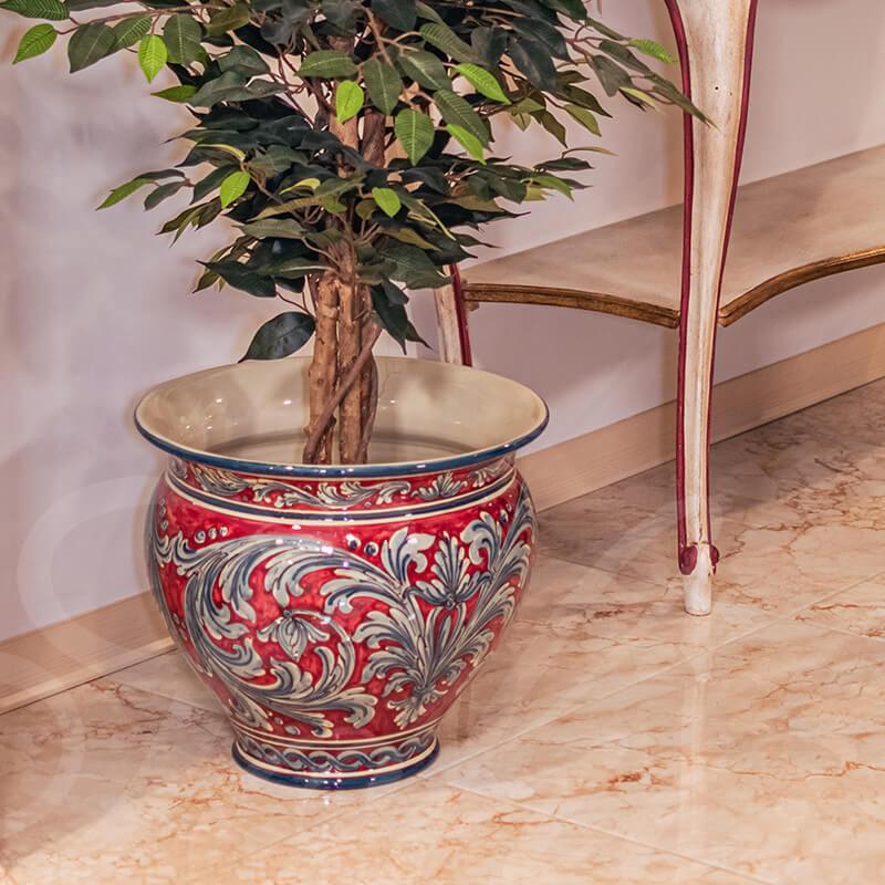 Vaso in ceramica di Caltagirone fatta a mano, decorato con motivi floreali rossi e blu, con pianta verde.